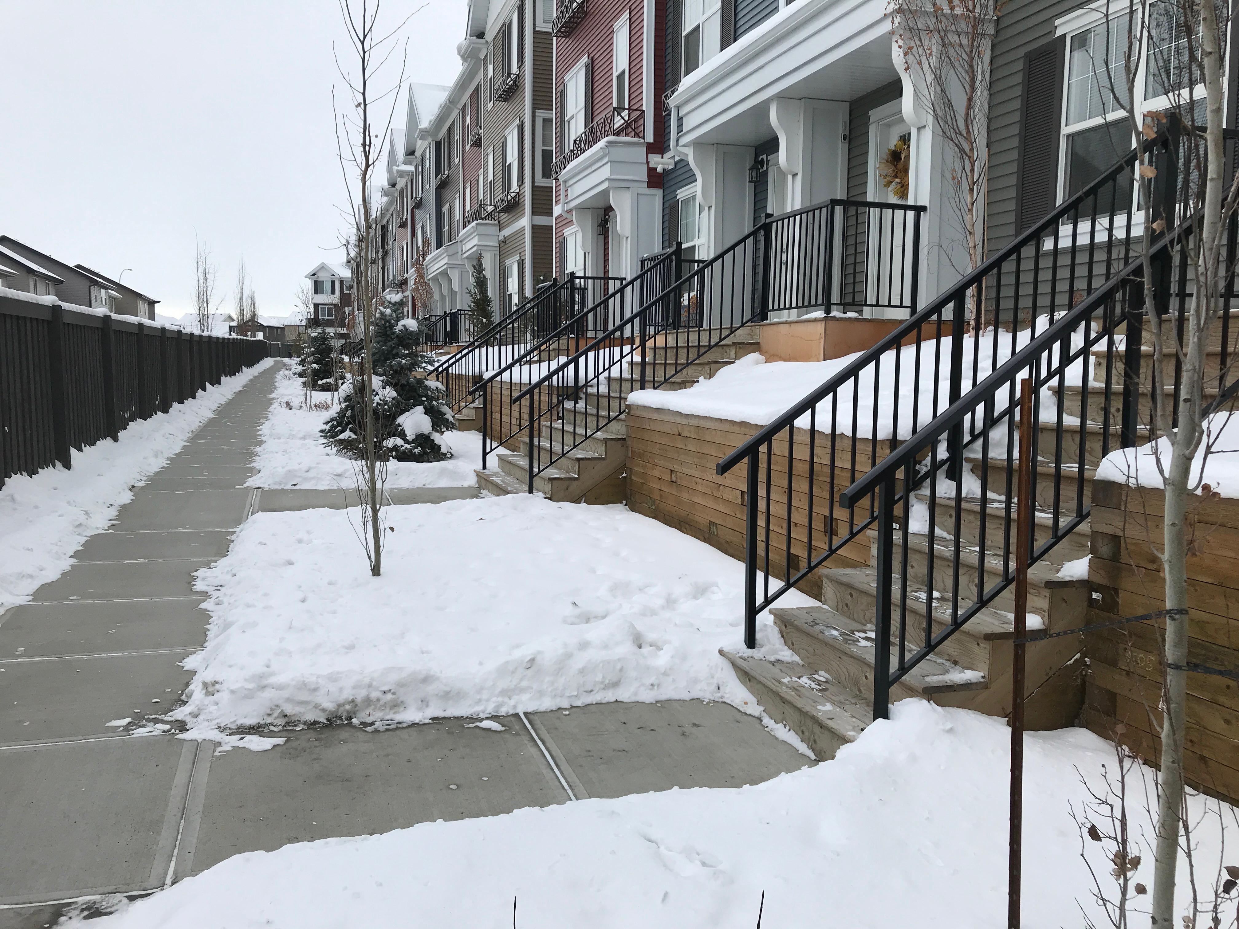 Townhouse row with cleared sidewalk and driveways in winter conditions